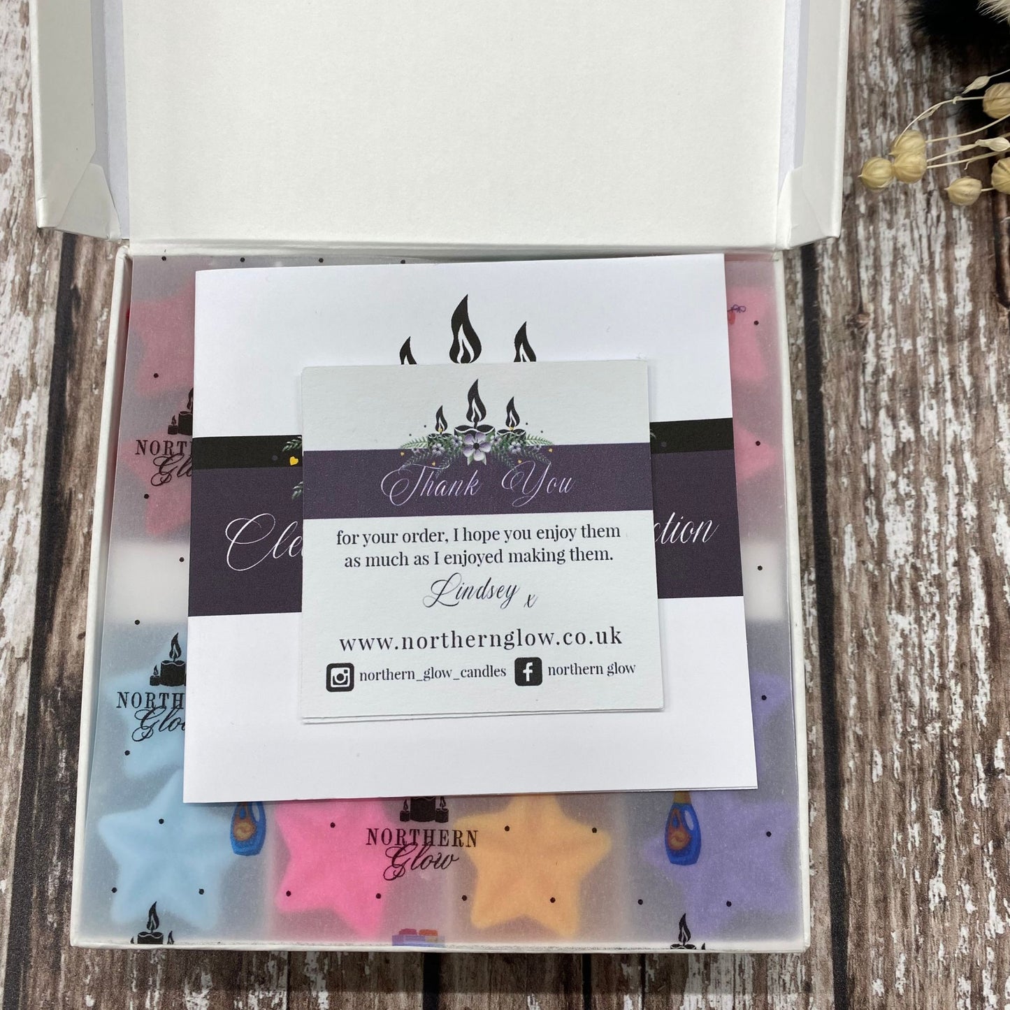 Northern Glow candle packaging with a business card on a wooden surface