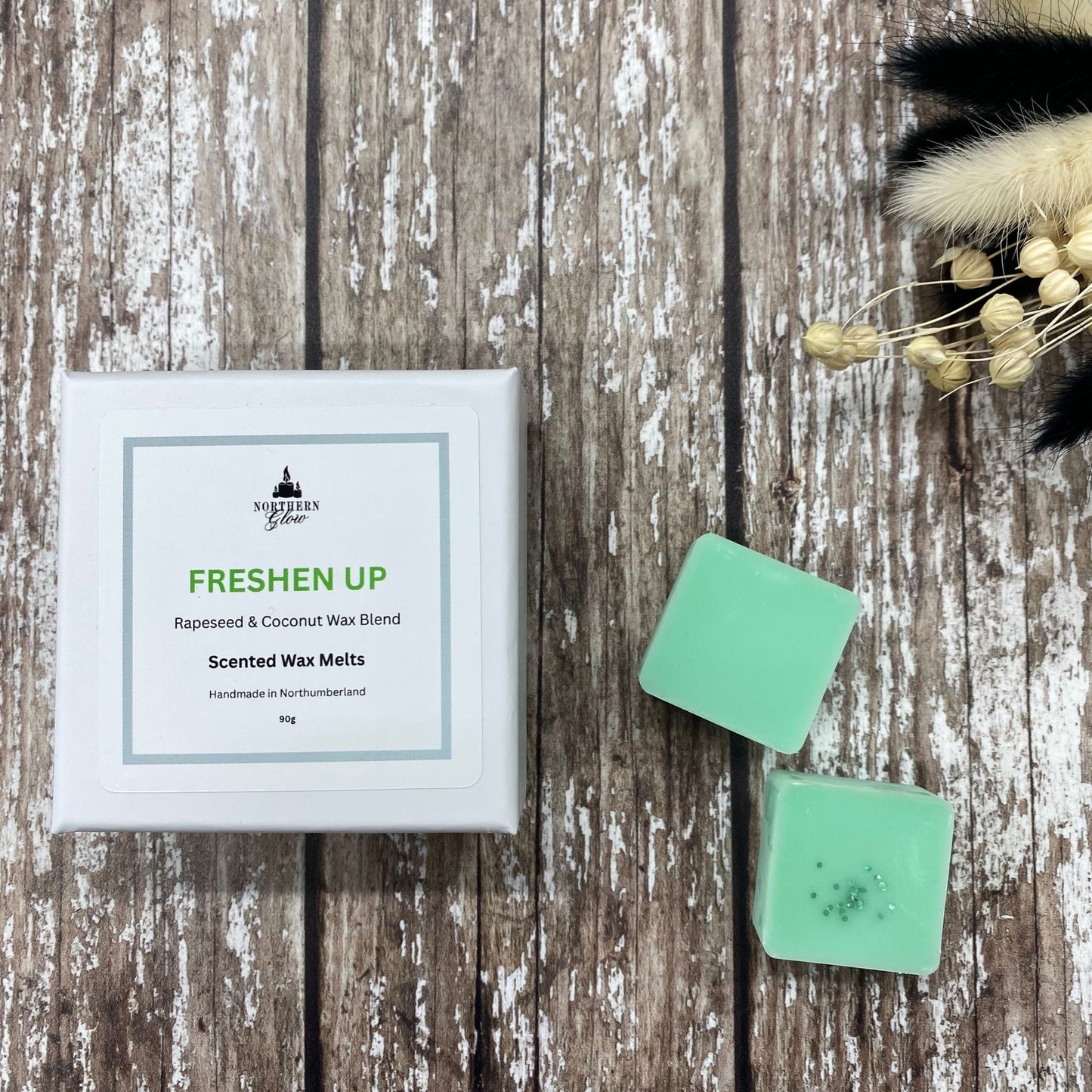 Freshen Up wax melt is a green colour and each melt is a square shape in a white box. There are eight individual wax melts in the white box. The label is white with a silver border. The logo is at the top with 'Freshen Up' in green writing, in the centre.