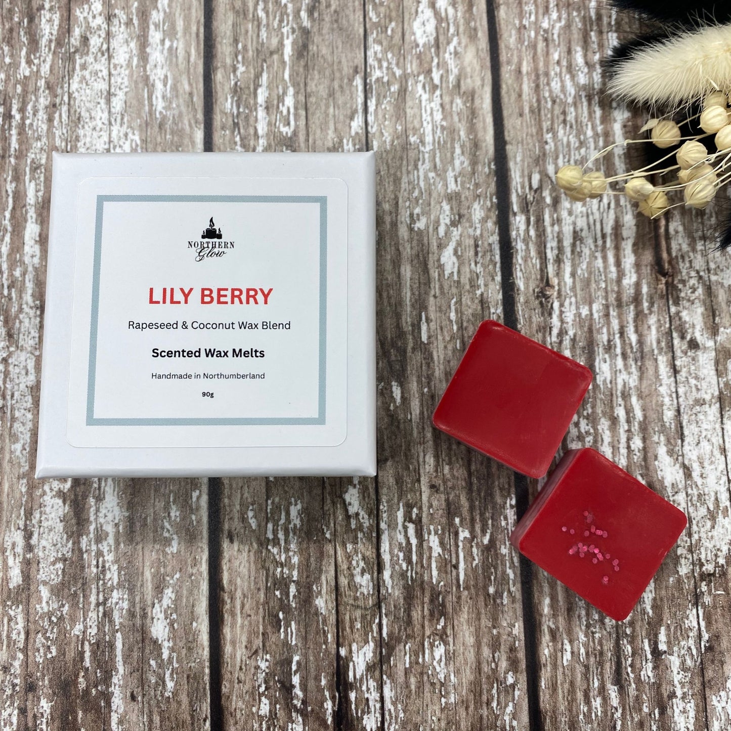 Red wax melts in a white square box sitting on a wood background