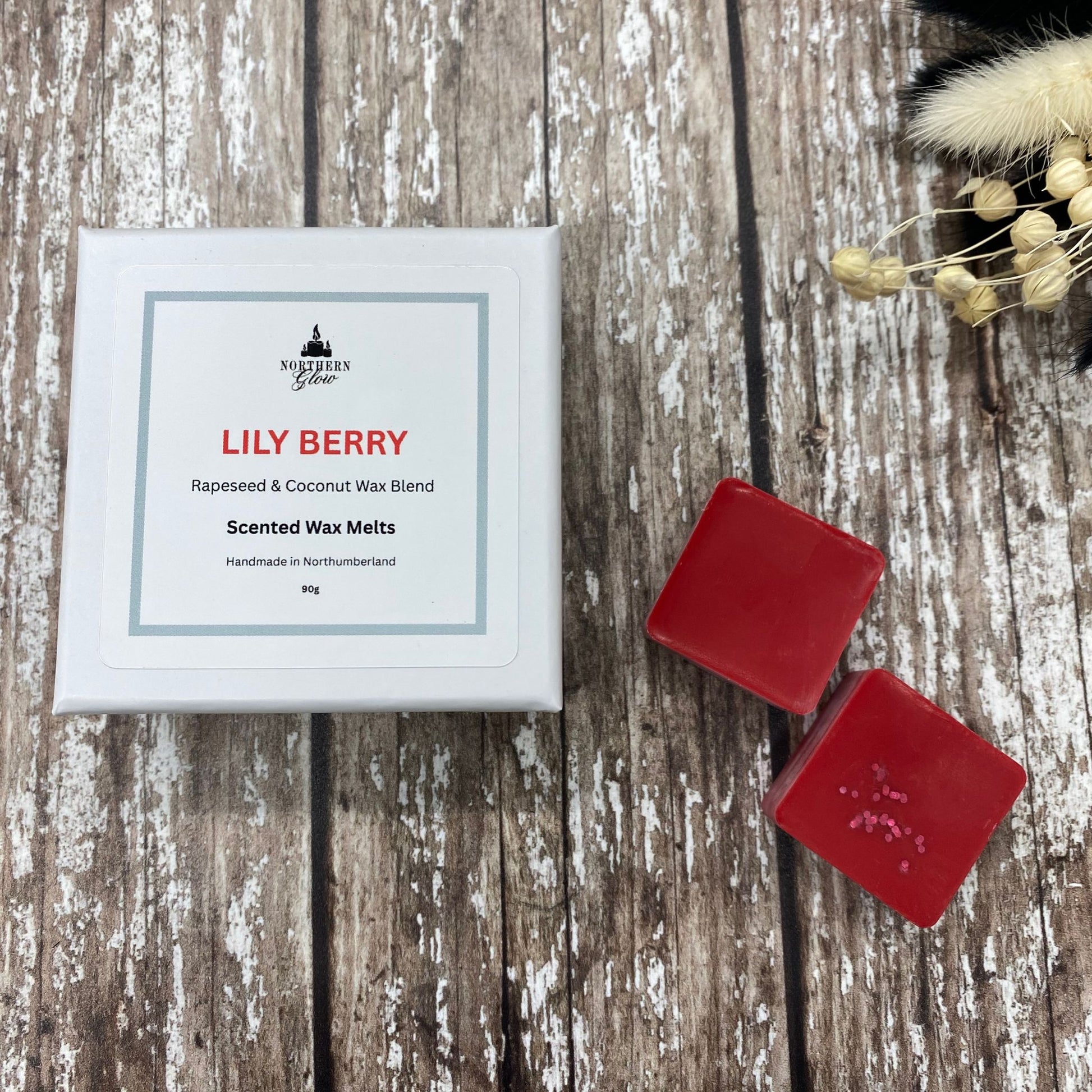 Red wax melts in a white square box sitting on a wood background