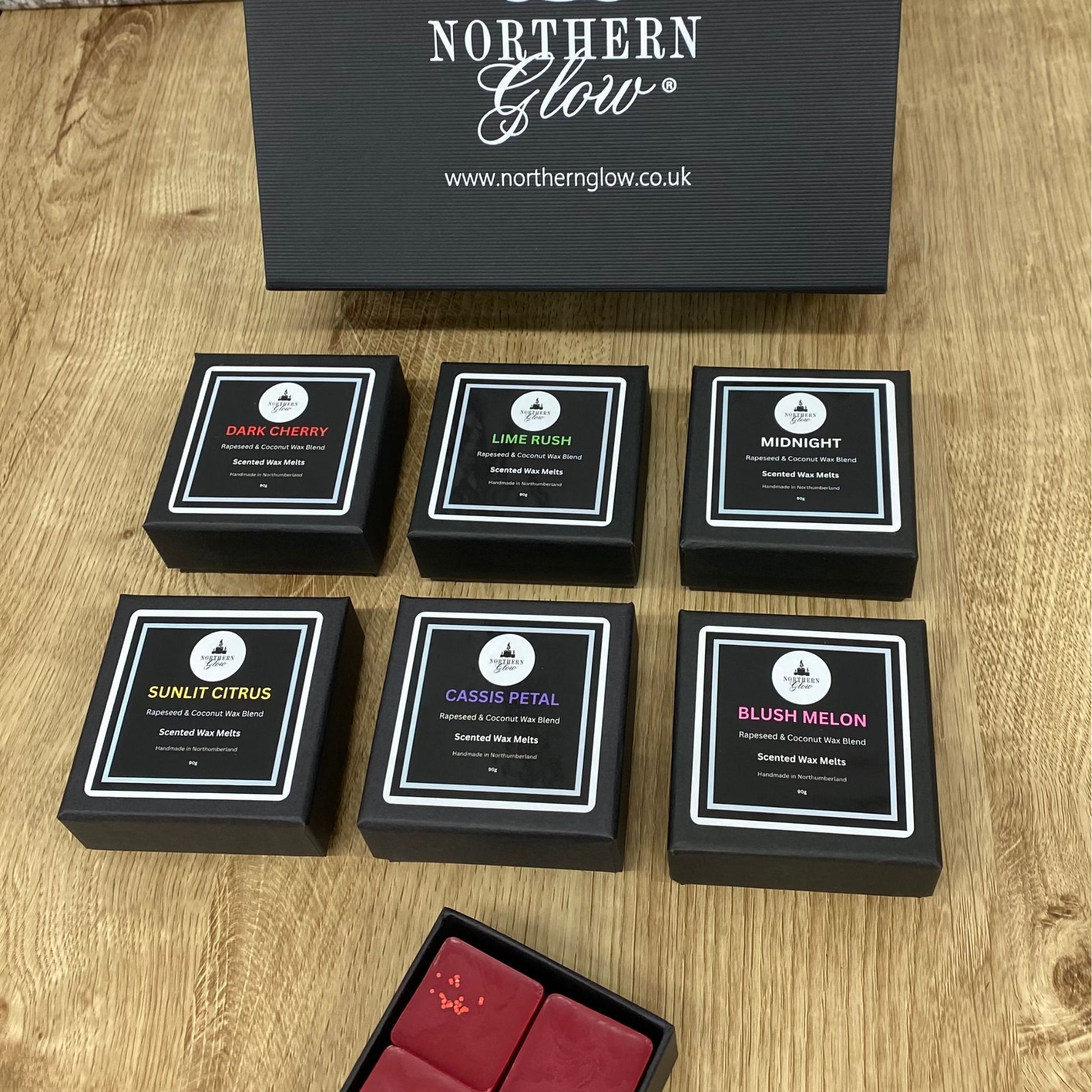 Set of black boxes with product names on a wooden surface, branded 'Northern Glow'.