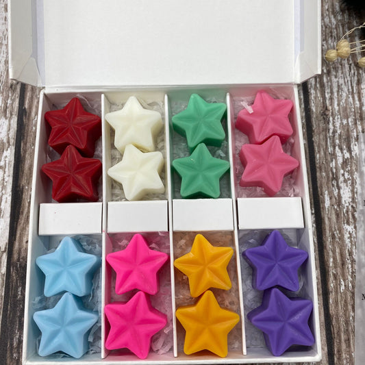 Box of colorful star-shaped candles on a wooden surface