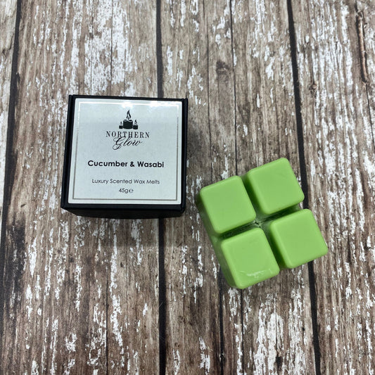 Green wax melts with packaging labeled 'Northern Glow Cucumber & Wasabi' on a wooden surface