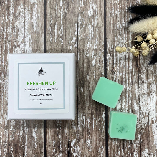 Freshen Up wax melt is a green colour and each melt is a square shape in a white box. There are eight individual wax melts in the white box. The label is white with a silver border. The logo is at the top with 'Freshen Up' in green writing, in the centre.