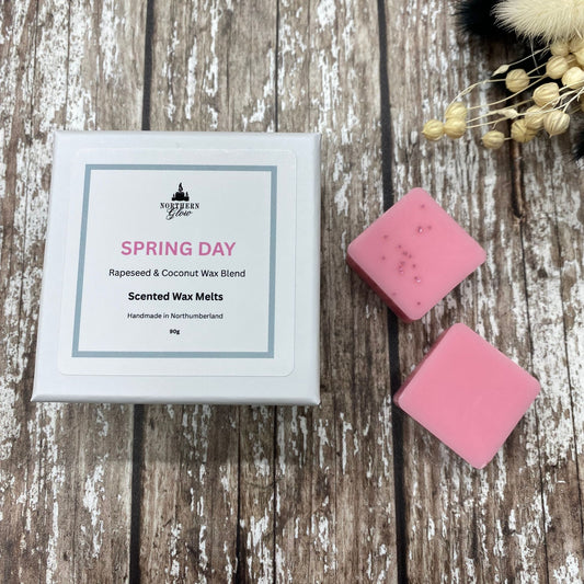Pink wax melts next to their packaging on a wooden surface